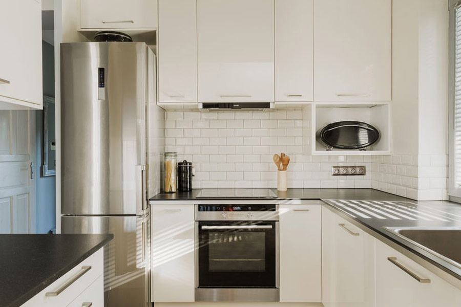 Una cocina con electrodomésticos de acero inoxidable y gabinetes blancos.