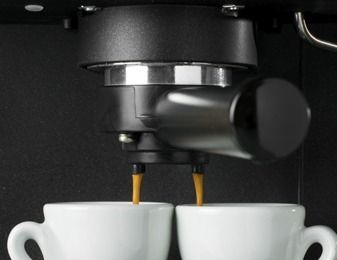 Se sirven dos tazas de café de una máquina.