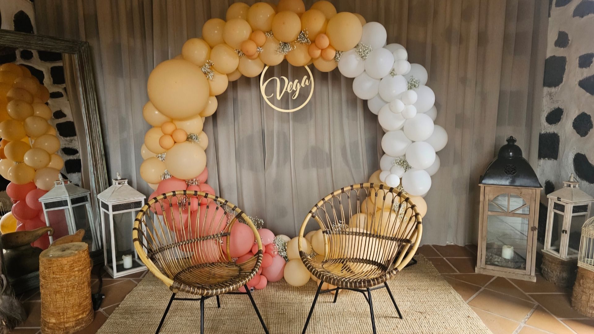 Dos sillas están sentadas frente a un arco de globos.