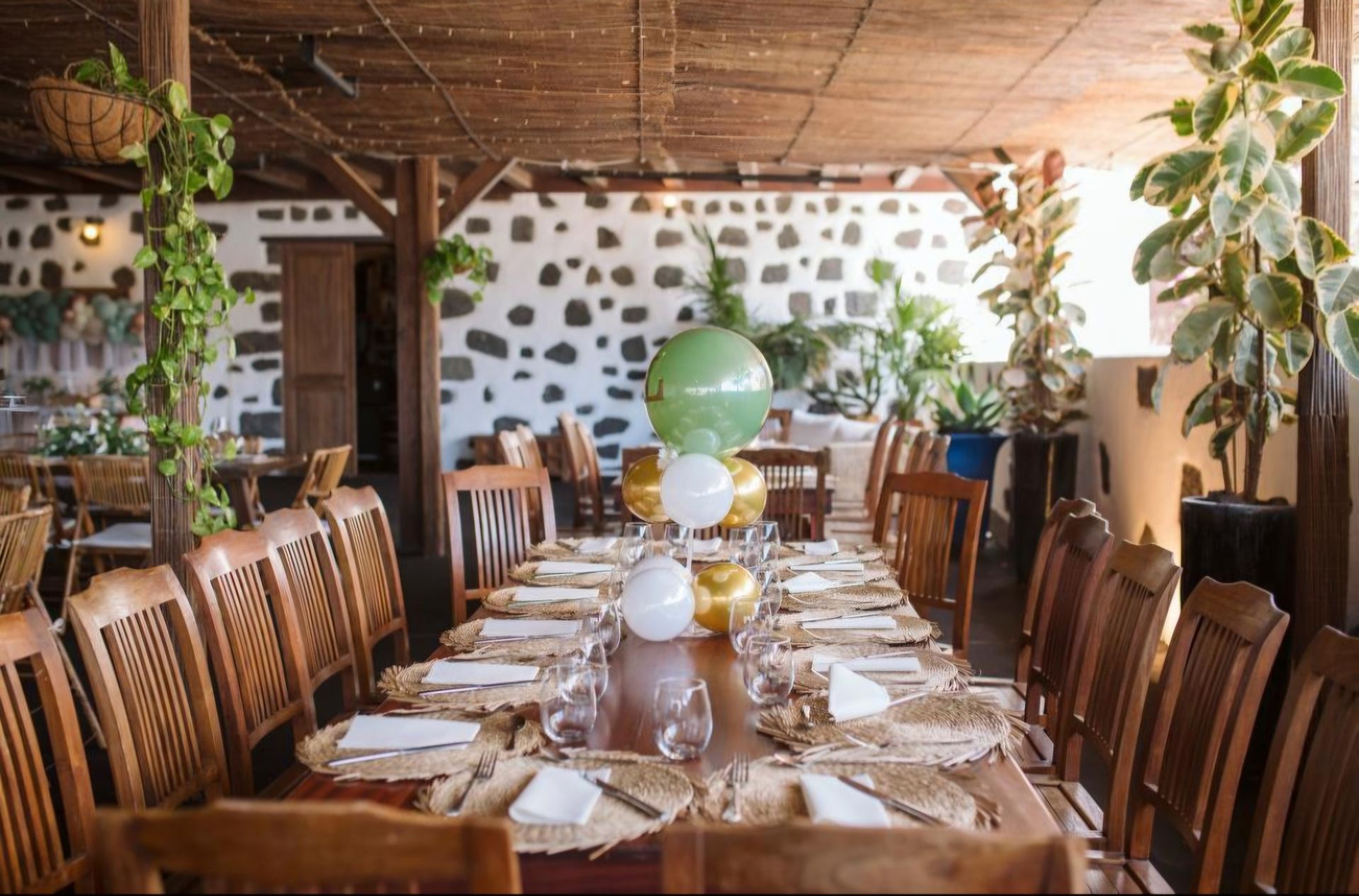 Una mesa larga en un restaurante con globos encima.