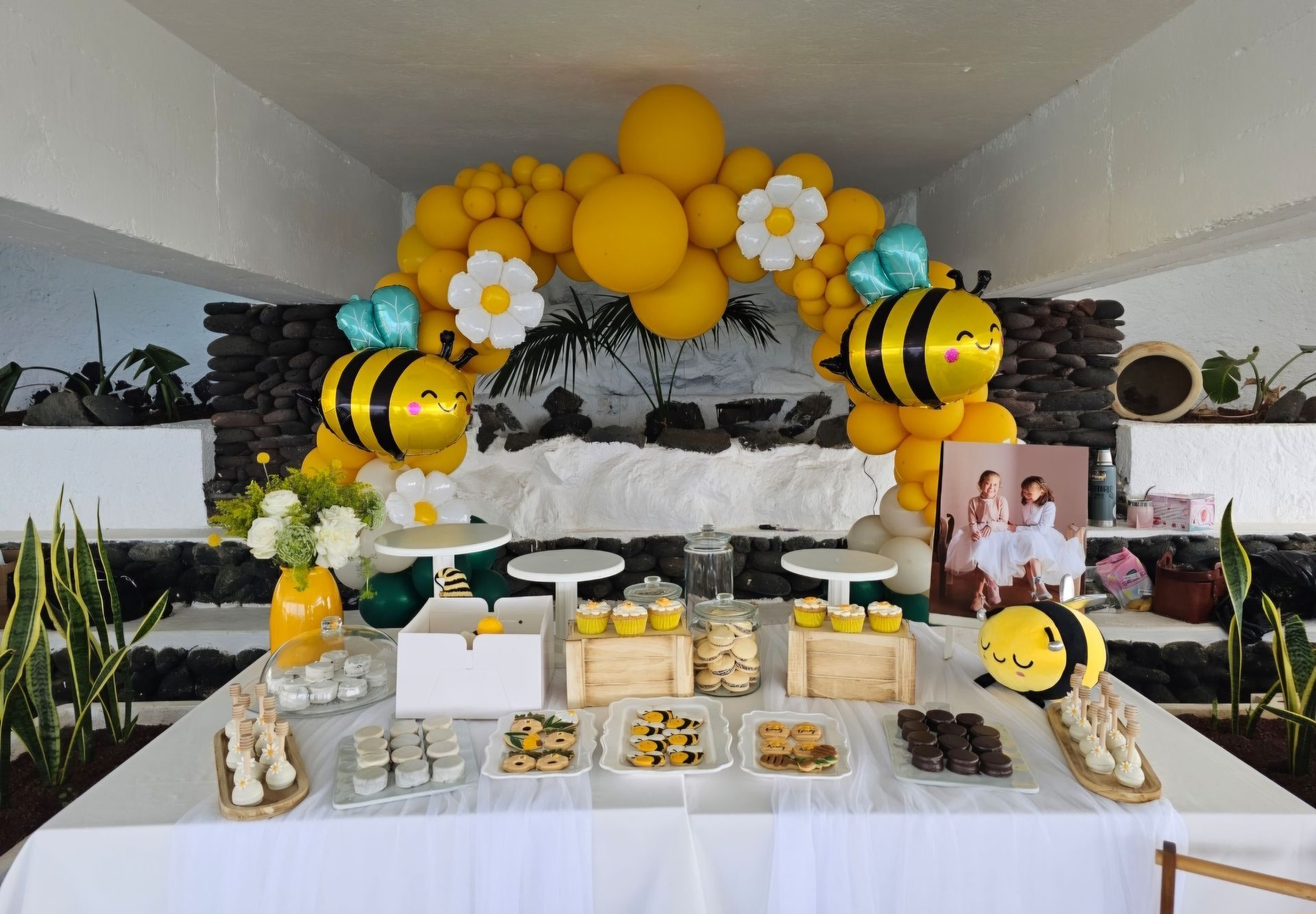 Una mesa decorada con globos amarillos y abejas para una fiesta de cumpleaños con temática de abejas.