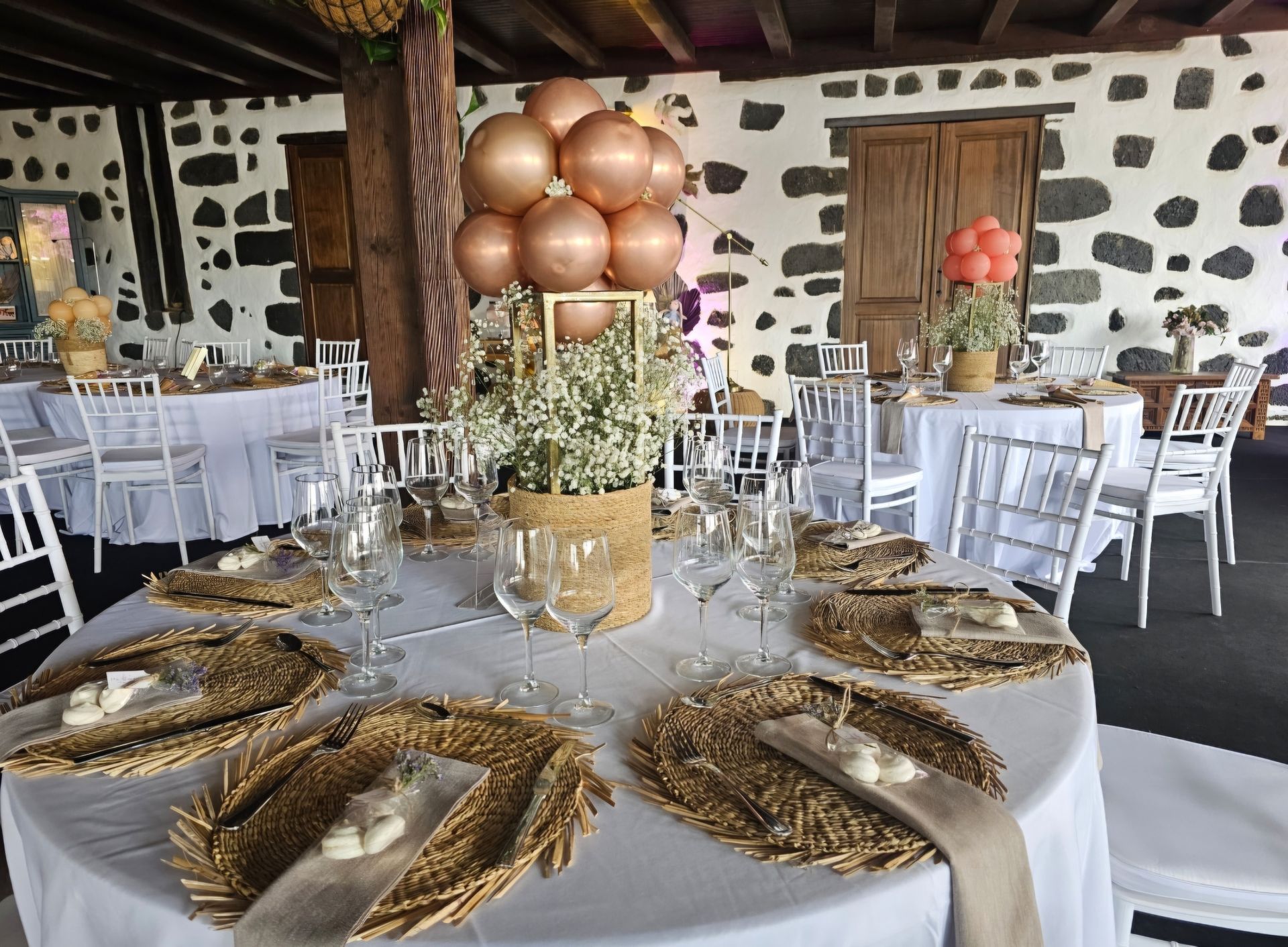 Una mesa preparada para una recepción de boda con platos, vasos y globos.