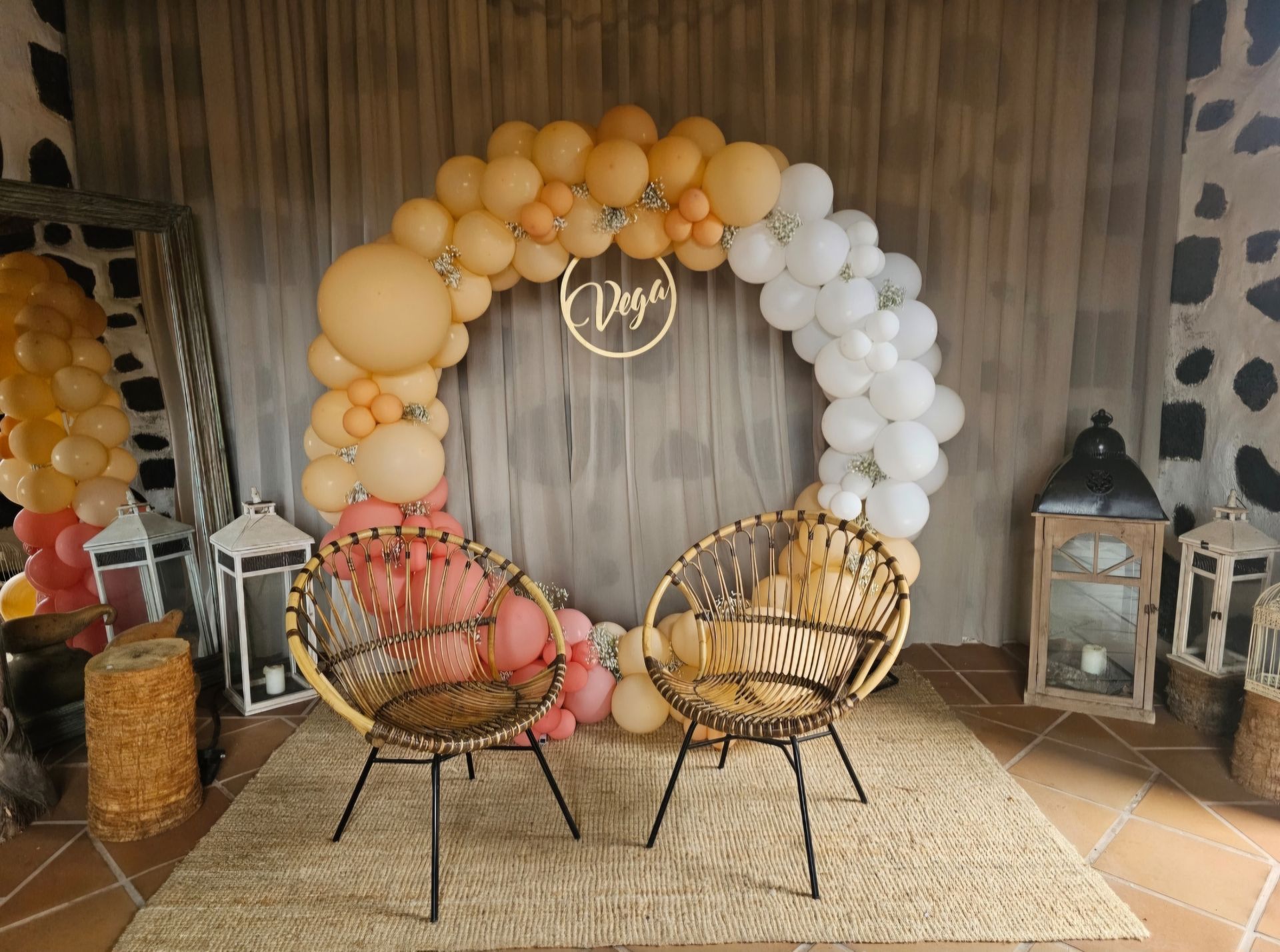 Dos sillas están sentadas frente a un arco de globos.