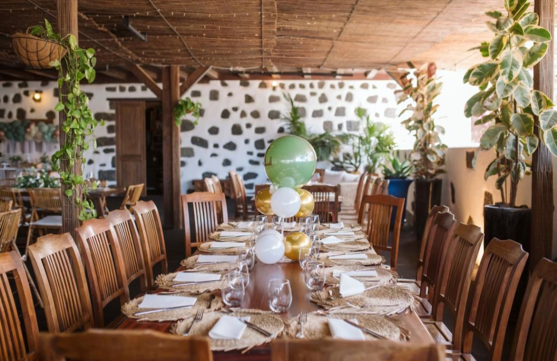 Una mesa larga en un restaurante con globos encima.