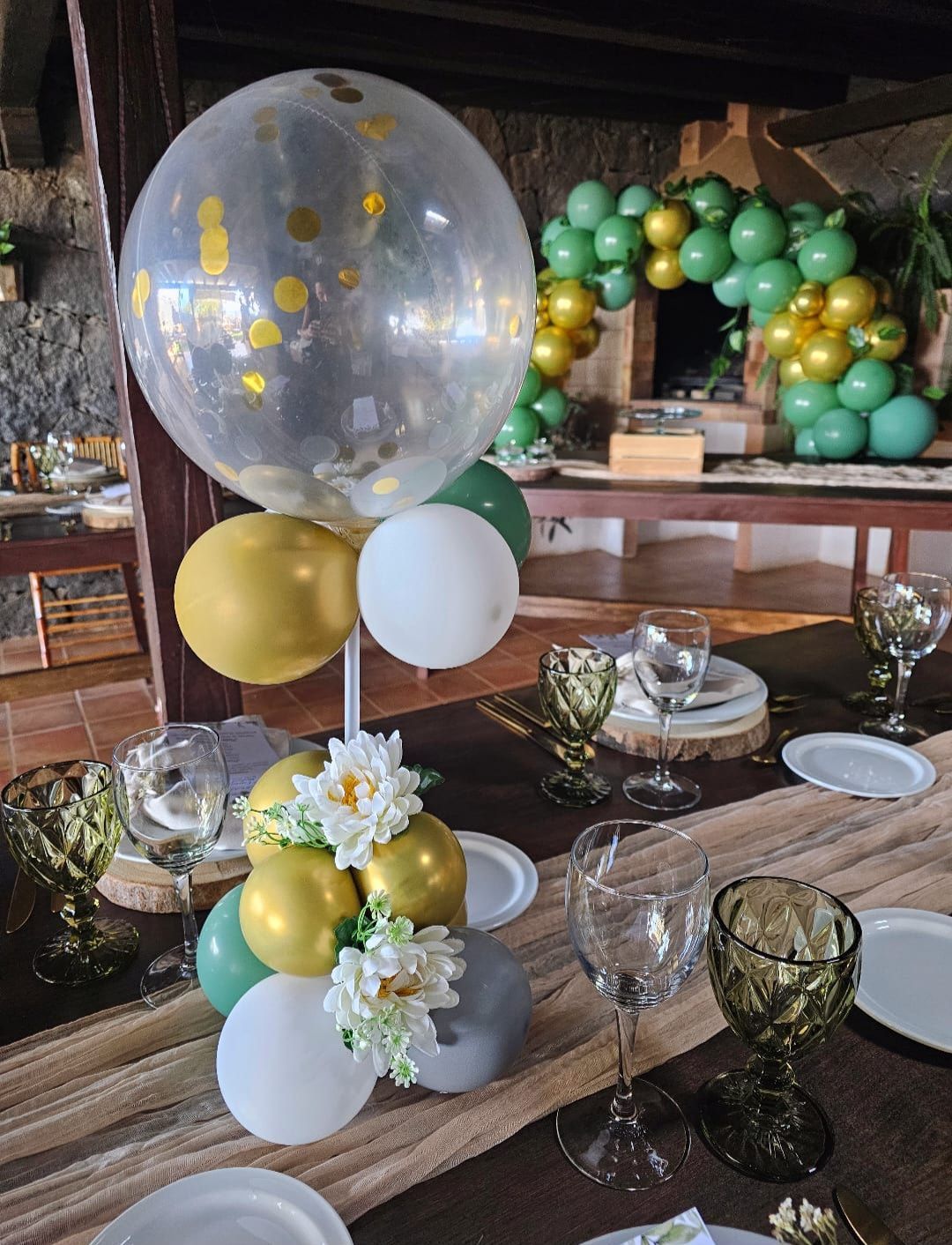 Una mesa con platos, vasos y globos encima.