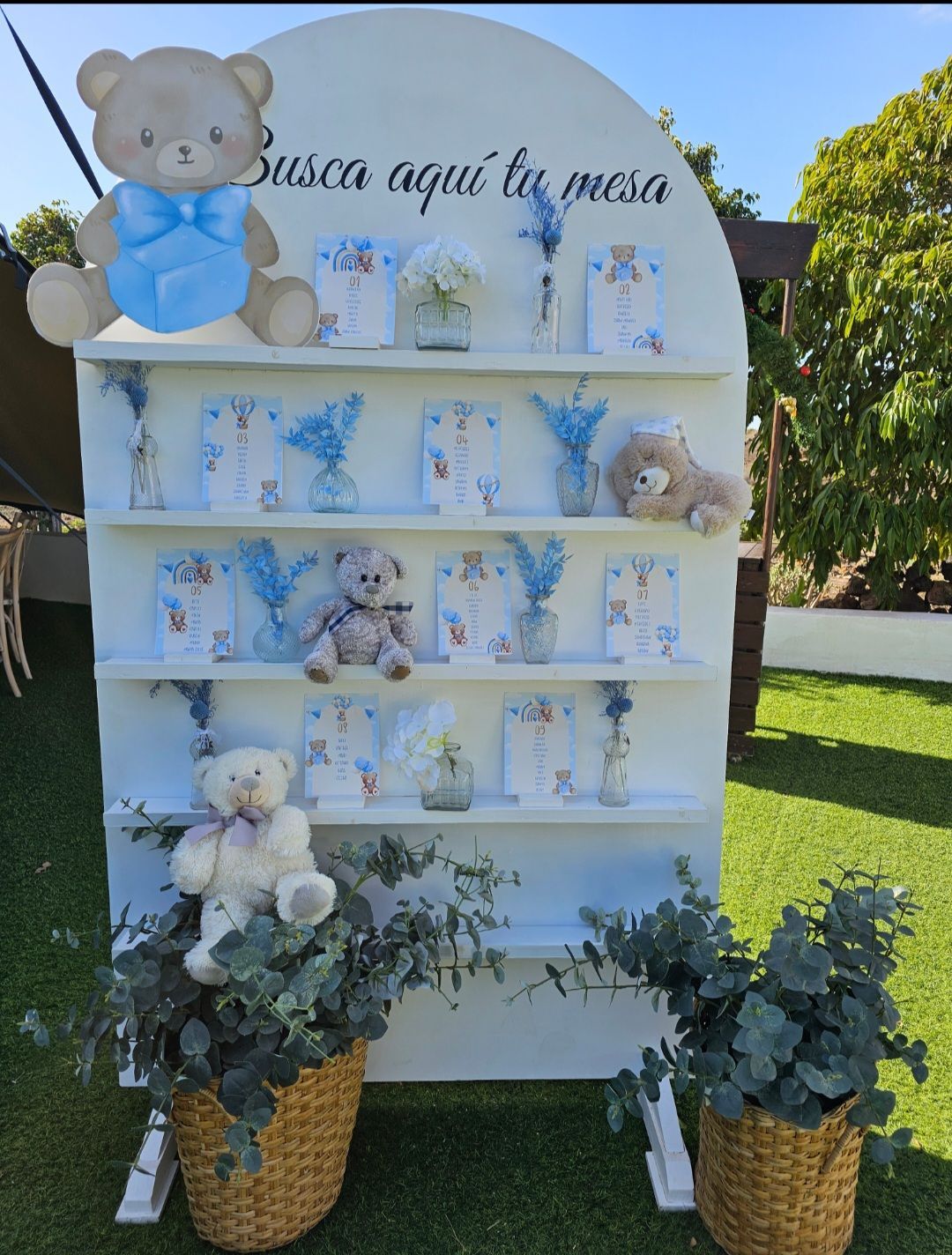 Una pared blanca con un osito de peluche que dice Busca aquí tu mesa