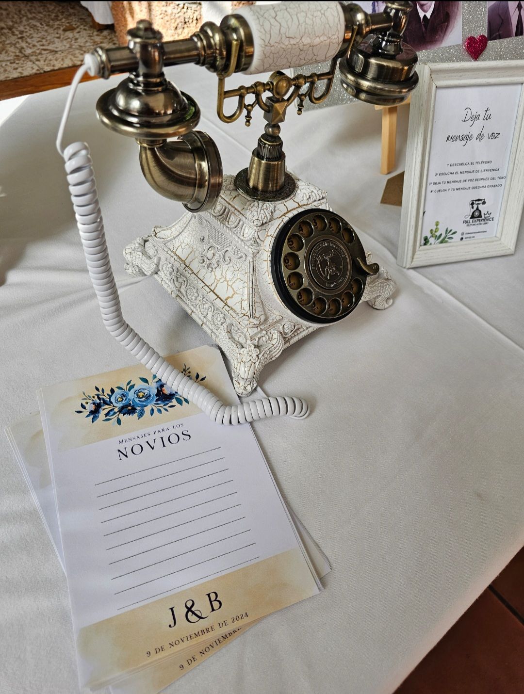 Un teléfono viejo está sobre una mesa junto a un cartel que dice J & B.
