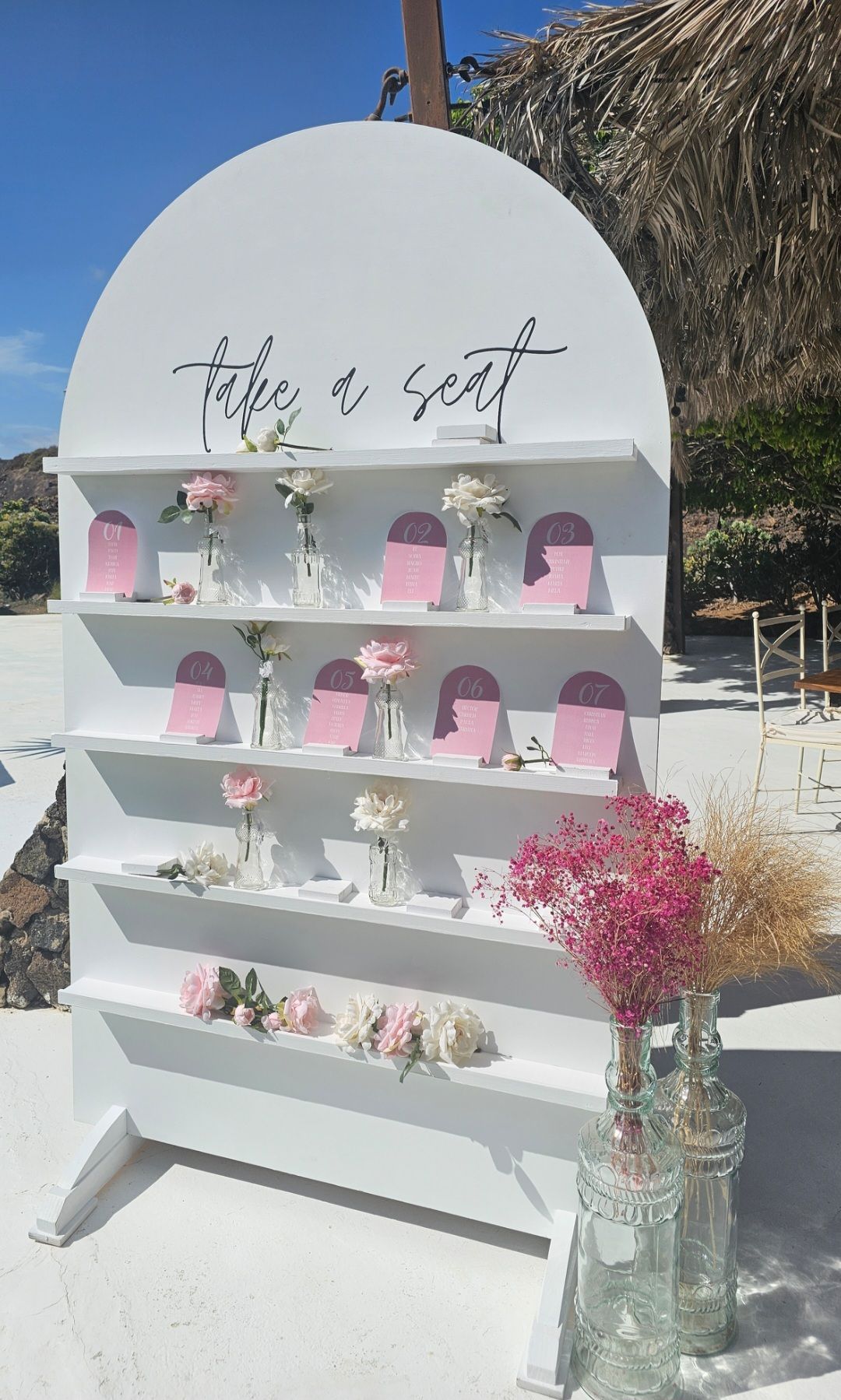 Un estante blanco lleno de jarrones con flores y tarjetas.