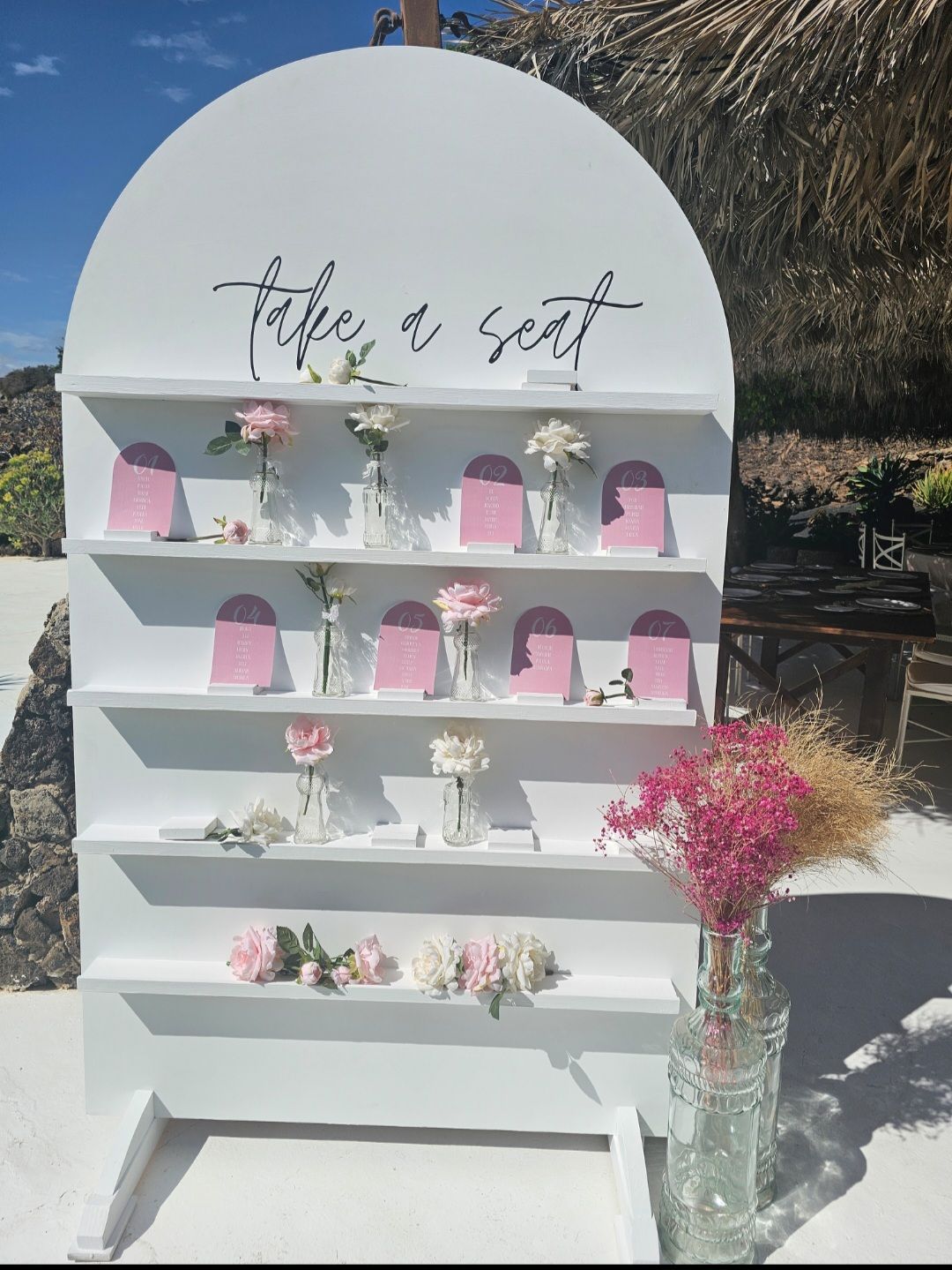 Una pared blanca con estantes llenos de jarrones con flores.