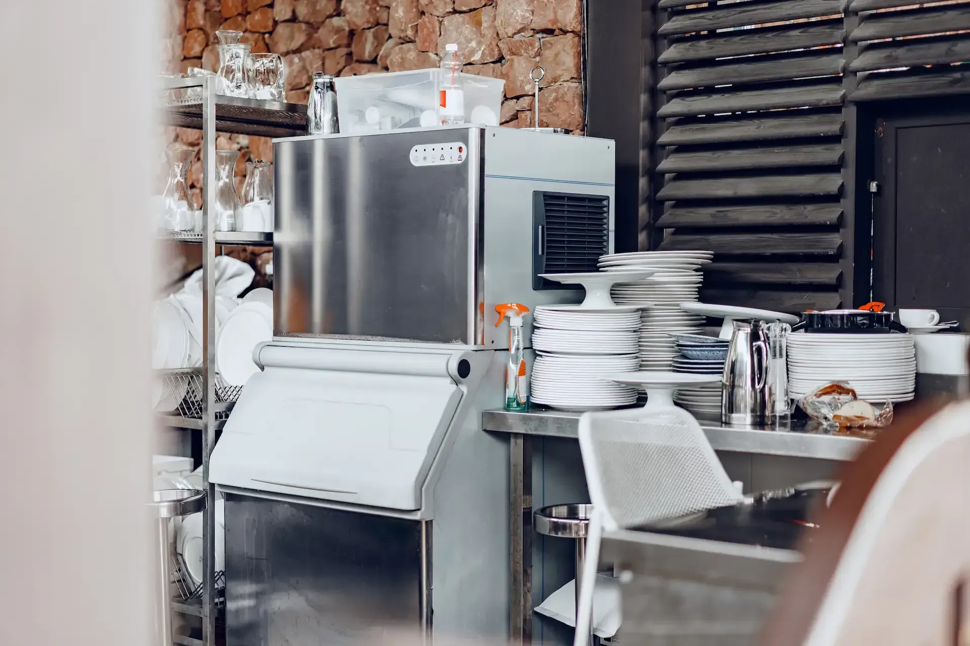 Bufé con exhibiciones de comida bajo brillantes lámparas de calor colgantes. Una persona está detrás del mostrador.