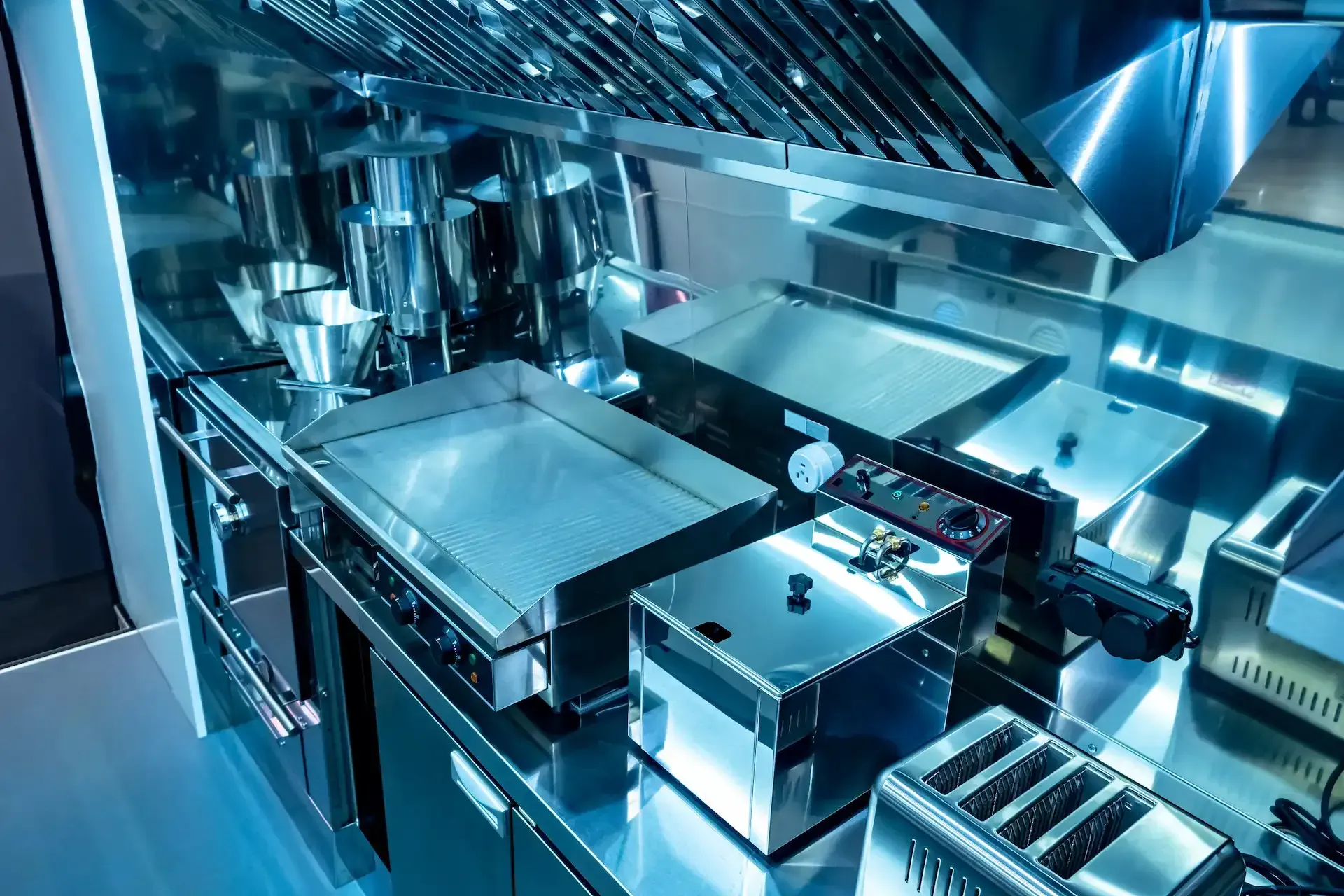 Bufé con exhibiciones de comida bajo brillantes lámparas de calor colgantes. Una persona está detrás del mostrador.