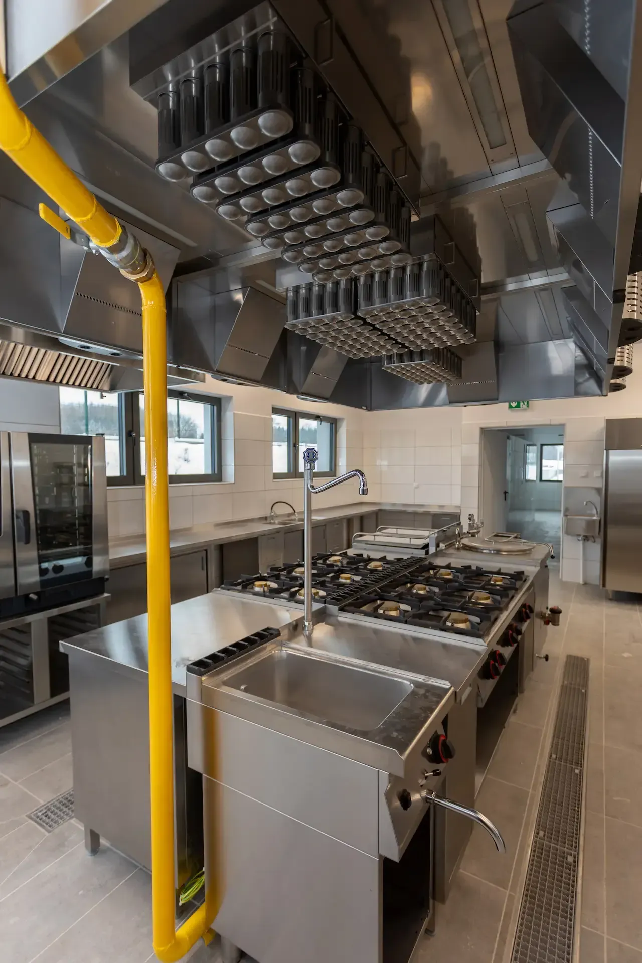 Bufé con exhibiciones de comida bajo brillantes lámparas de calor colgantes. Una persona está detrás del mostrador.