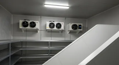 Bufé con exhibiciones de comida bajo brillantes lámparas de calor colgantes. Una persona está detrás del mostrador.