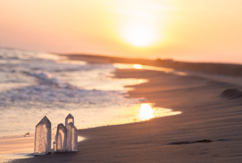 Trois cristaux sont assis sur la plage au coucher du soleil.