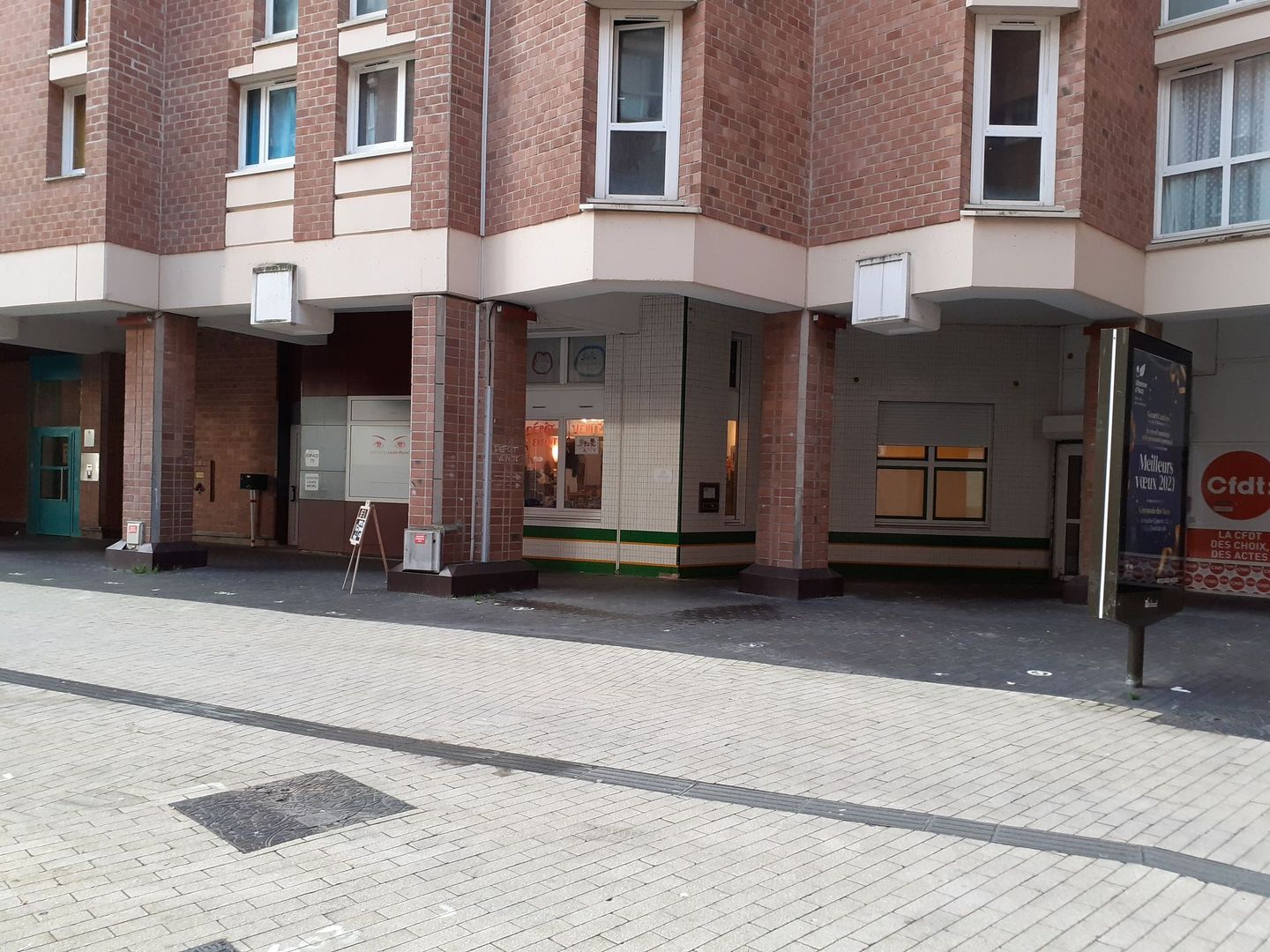 Un bâtiment en briques avec beaucoup de fenêtres et un trottoir devant