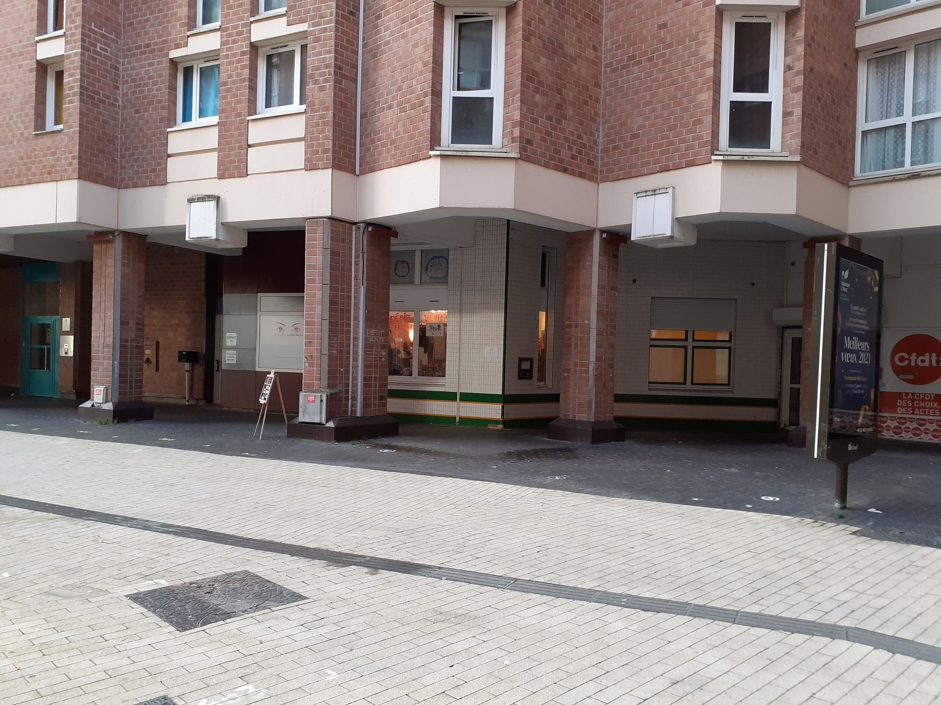 Un bâtiment en briques avec beaucoup de fenêtres et un trottoir devant