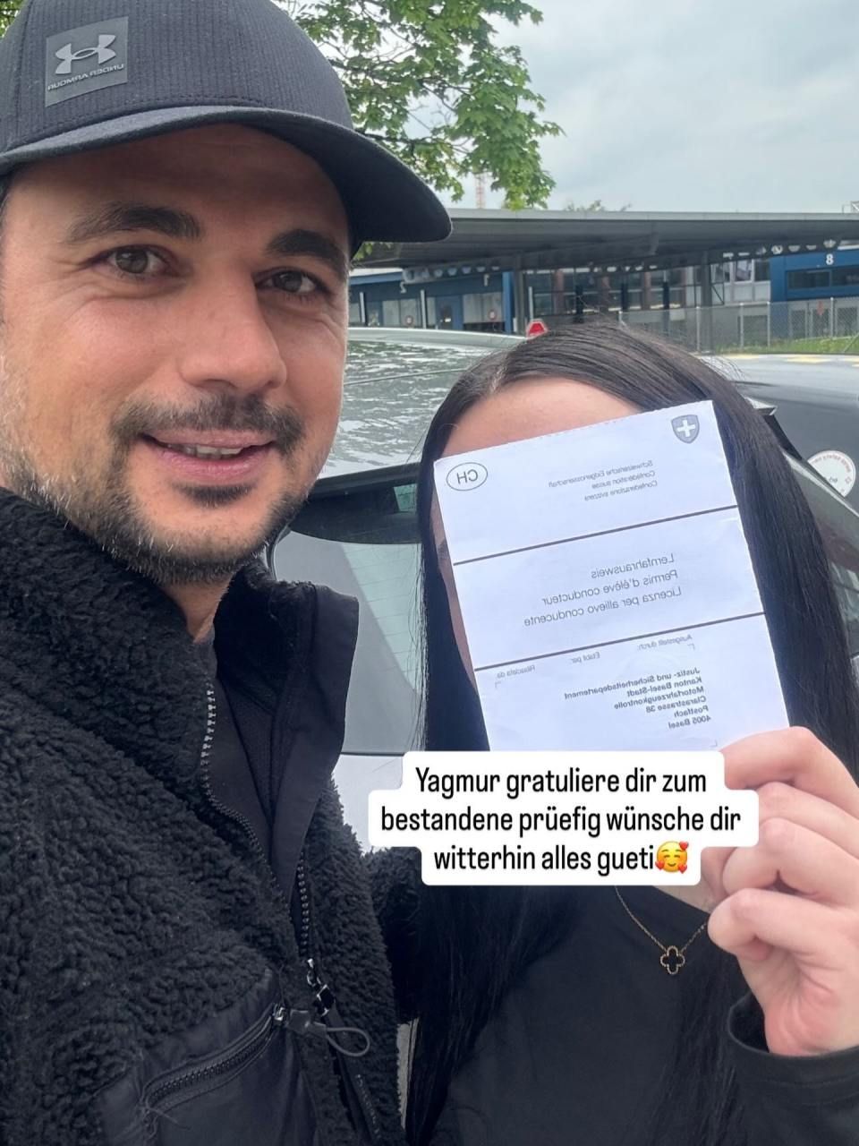 Mann und Frau halten im Freien eine Glückwunschurkunde mit deutschem Textüberlagerung.