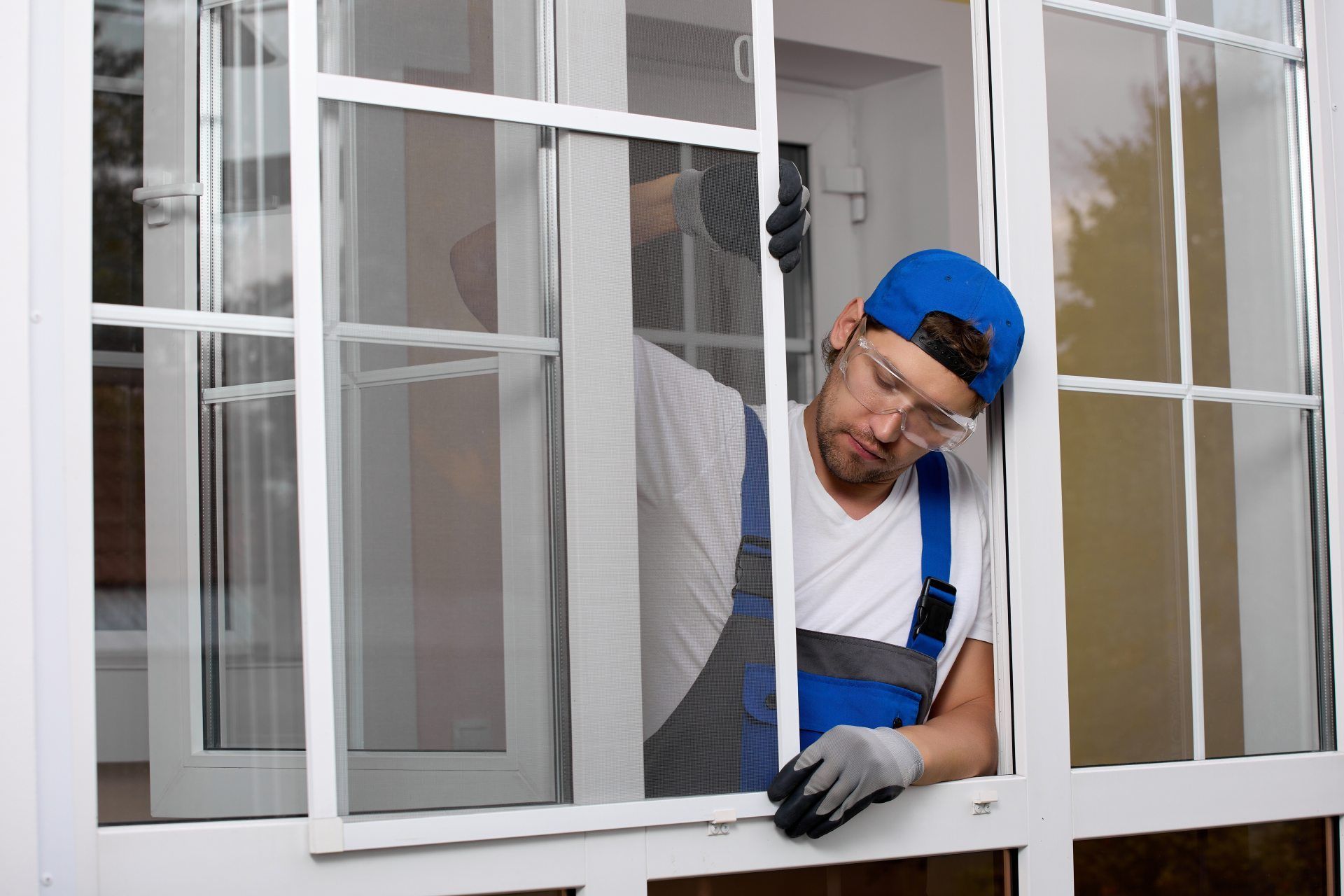 Foto eines Handwerkers, der ein Insektenschutzgitter am Fenster anbringt