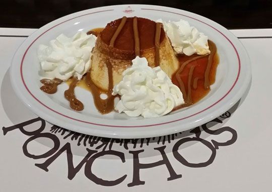 Un plato de comida con crema batida y caramelo sobre una mesa con la palabra poncho escrita en él.