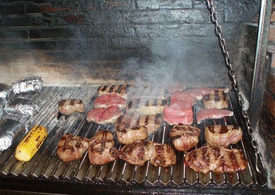 Un montón de carne se está cocinando en una parrilla.