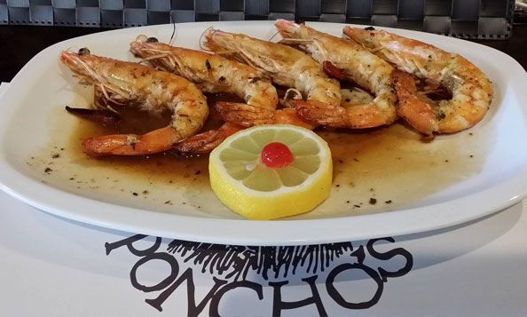 Un plato de camarones con limón y una cereza encima.