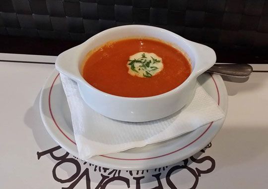 Un tazón de sopa de tomate con crema agria encima
