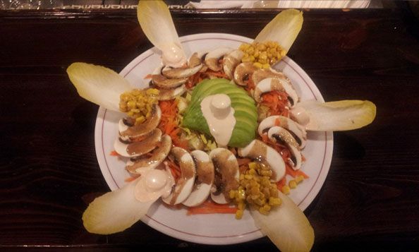 Una ensalada con champiñones y aguacate en un plato.