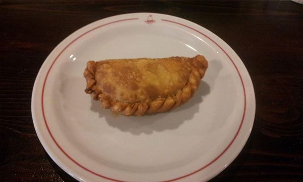 Un pastel frito en un plato blanco con una raya roja