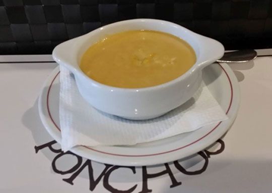 Un tazón de sopa se encuentra en un plato con la palabra poncho en él.
