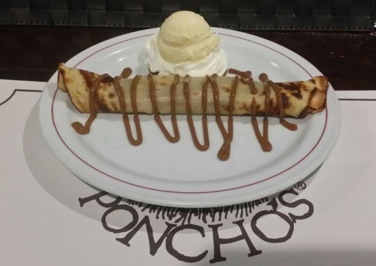 Un plato blanco con una crepe y helado encima.