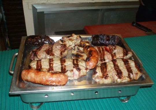 Una bandeja de carne y salchichas sobre una mesa