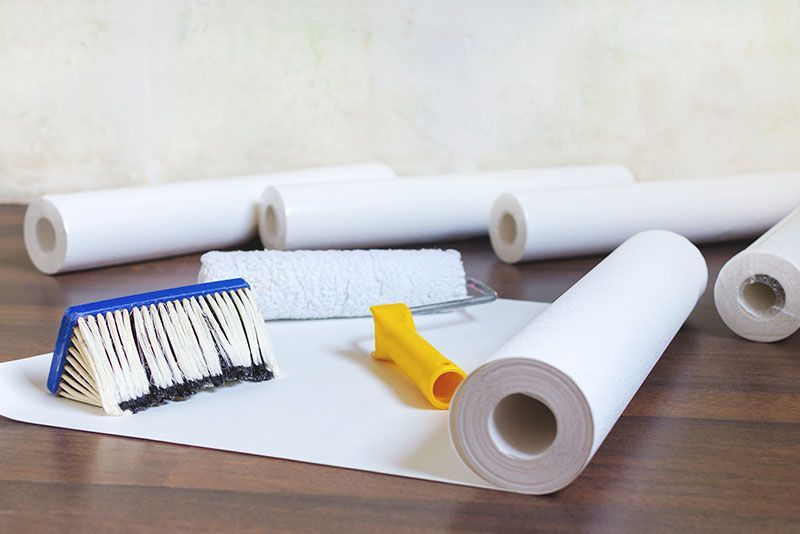 Tapetenrollen und Pinsel auf einem Holztisch