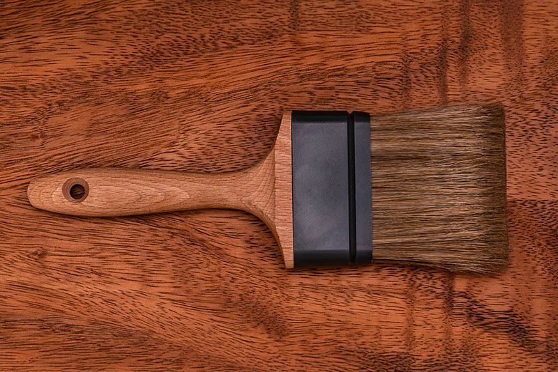 Ein Pinsel mit Holzgriff liegt auf einem Holztisch.
