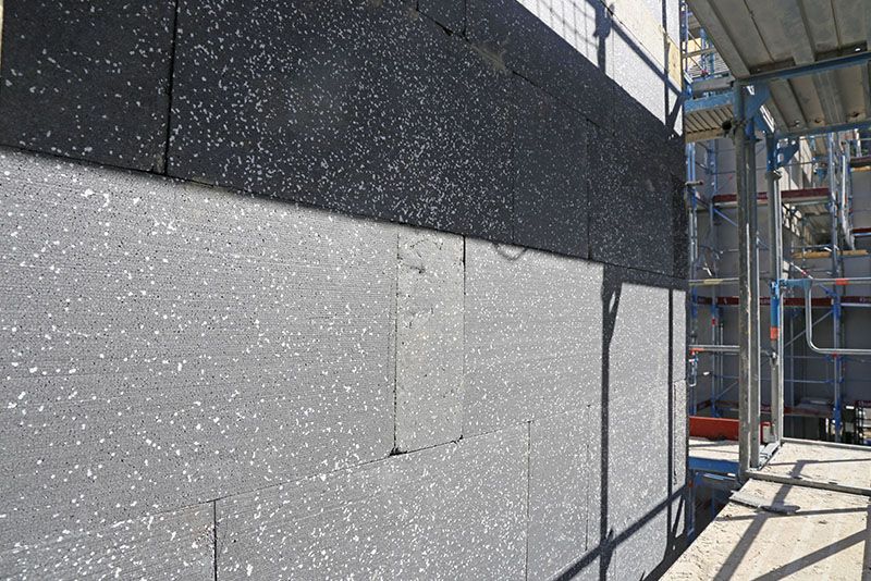 Auf einer Baustelle wird mit Gerüst eine Mauer errichtet.