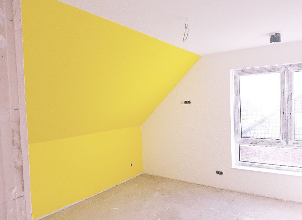 Ein leerer Raum mit einer gelben Wand und einem Fenster.