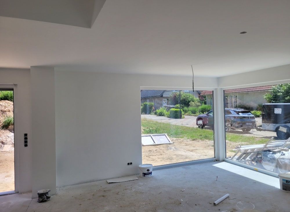 Ein Wohnzimmer mit einem großen Fenster und einer Glasschiebetür.