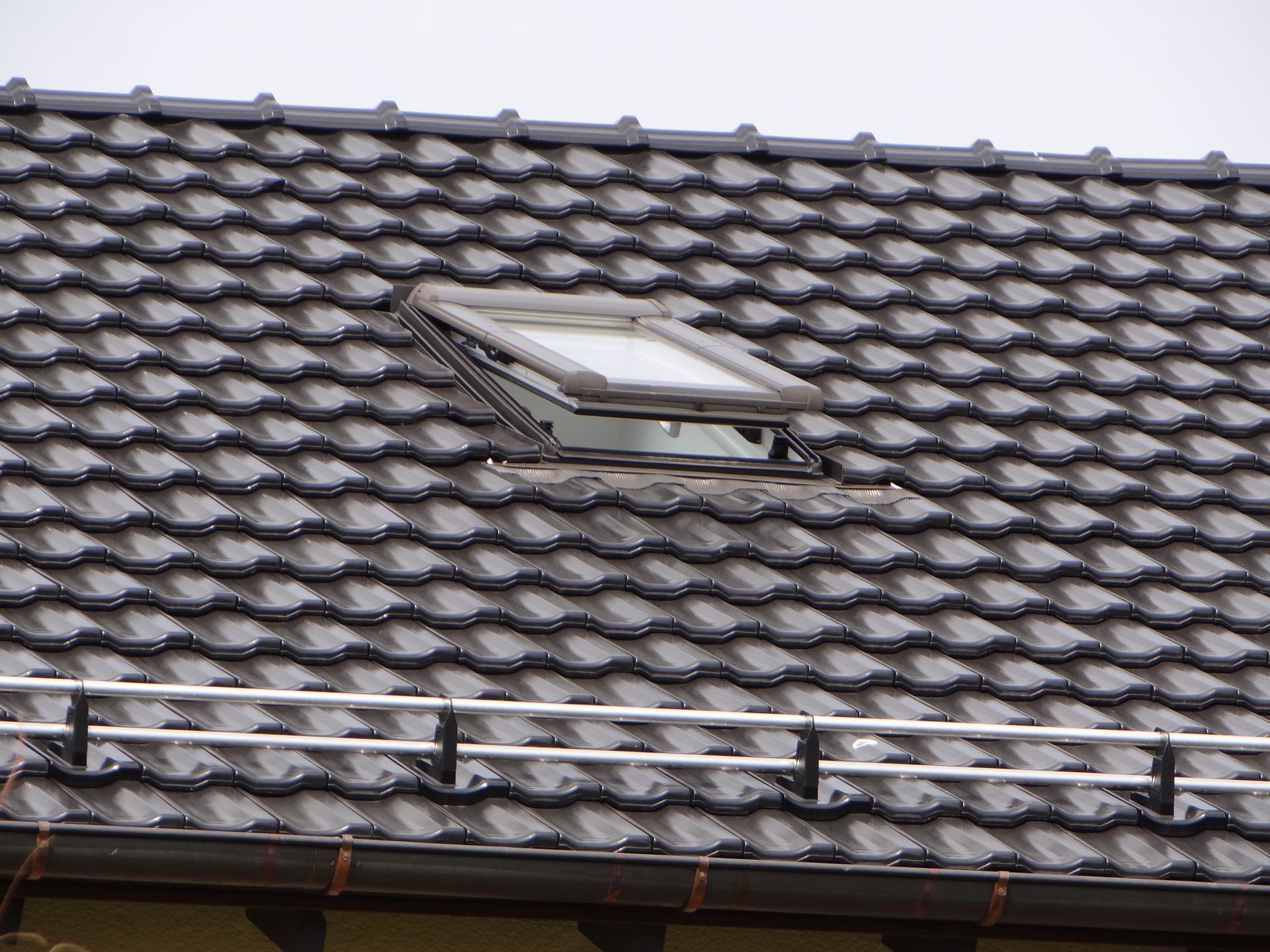 Tondachziegel mit integriertem Dachfenster auf geneigter Dachfläche.
