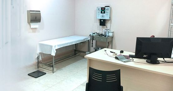 Un consultorio médico con un escritorio y una cama.