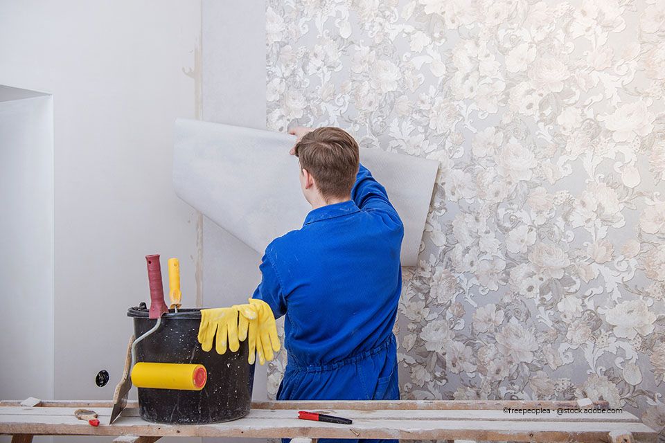 Mitarbeiter von Ausbau Fassaden Raumgestaltung Meisterbetrieb Alexander Linke tapeziert ein Wohnzimmer mit einer blumigen Tapete
