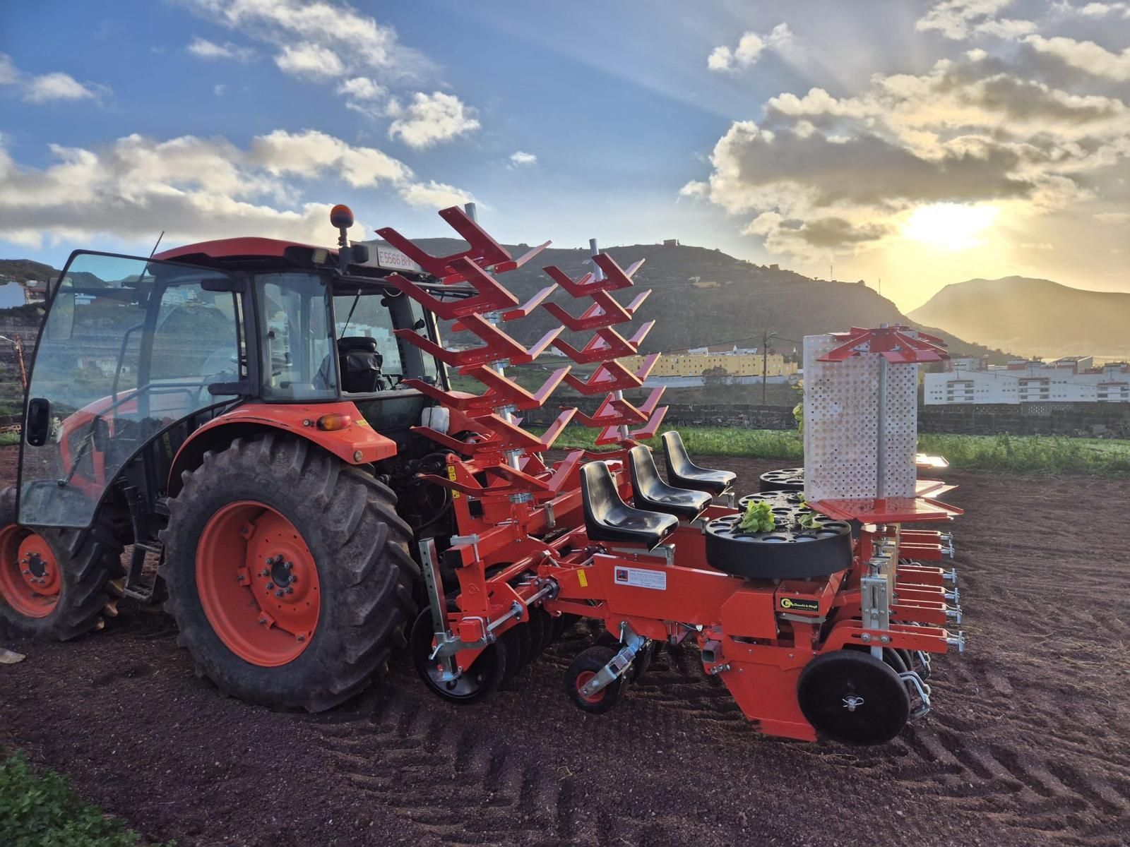Tractor Kubota naranja estacionado en un campo de hierba, vista frontal izquierda.