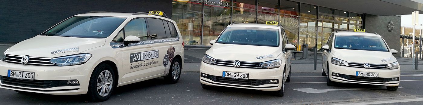 Drei weiße Taxis stehen nebeneinander