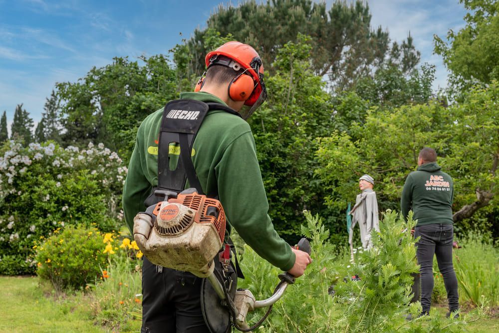 Employé avec un souffleur de feuille dans le jardin d'un particulier
