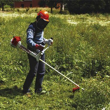 Ouvrier fauche un terrain herbeux à l'aide d'un rotofile
