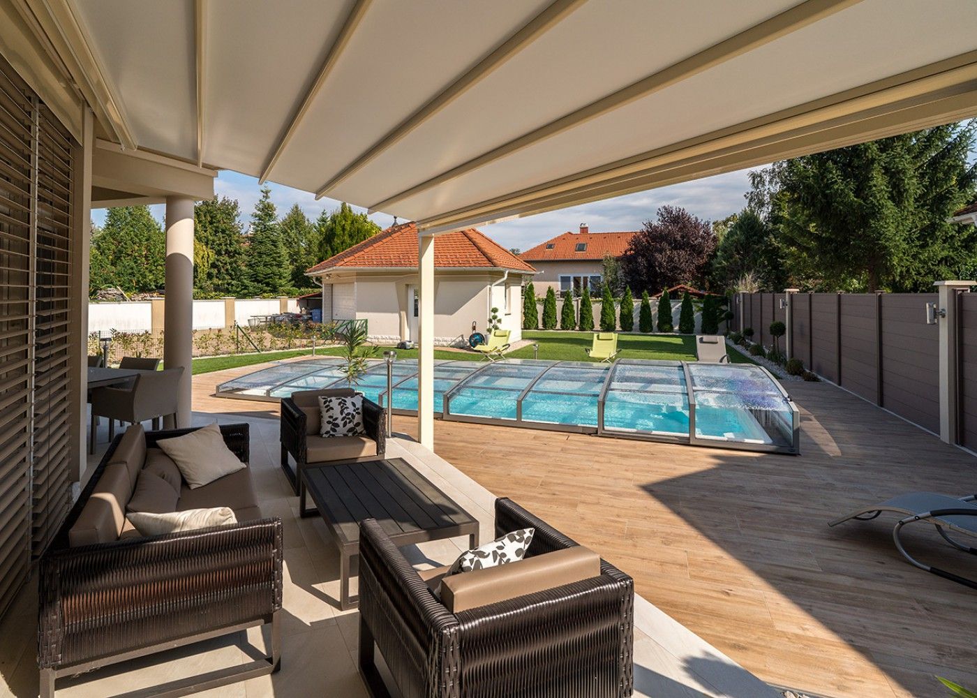 Terrasse aménagée devant une piscine et son abri