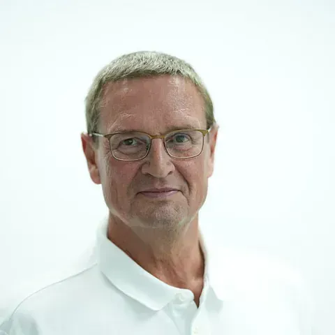 Ein Mann mit Brille und weißem Hemd schaut in die Kamera.