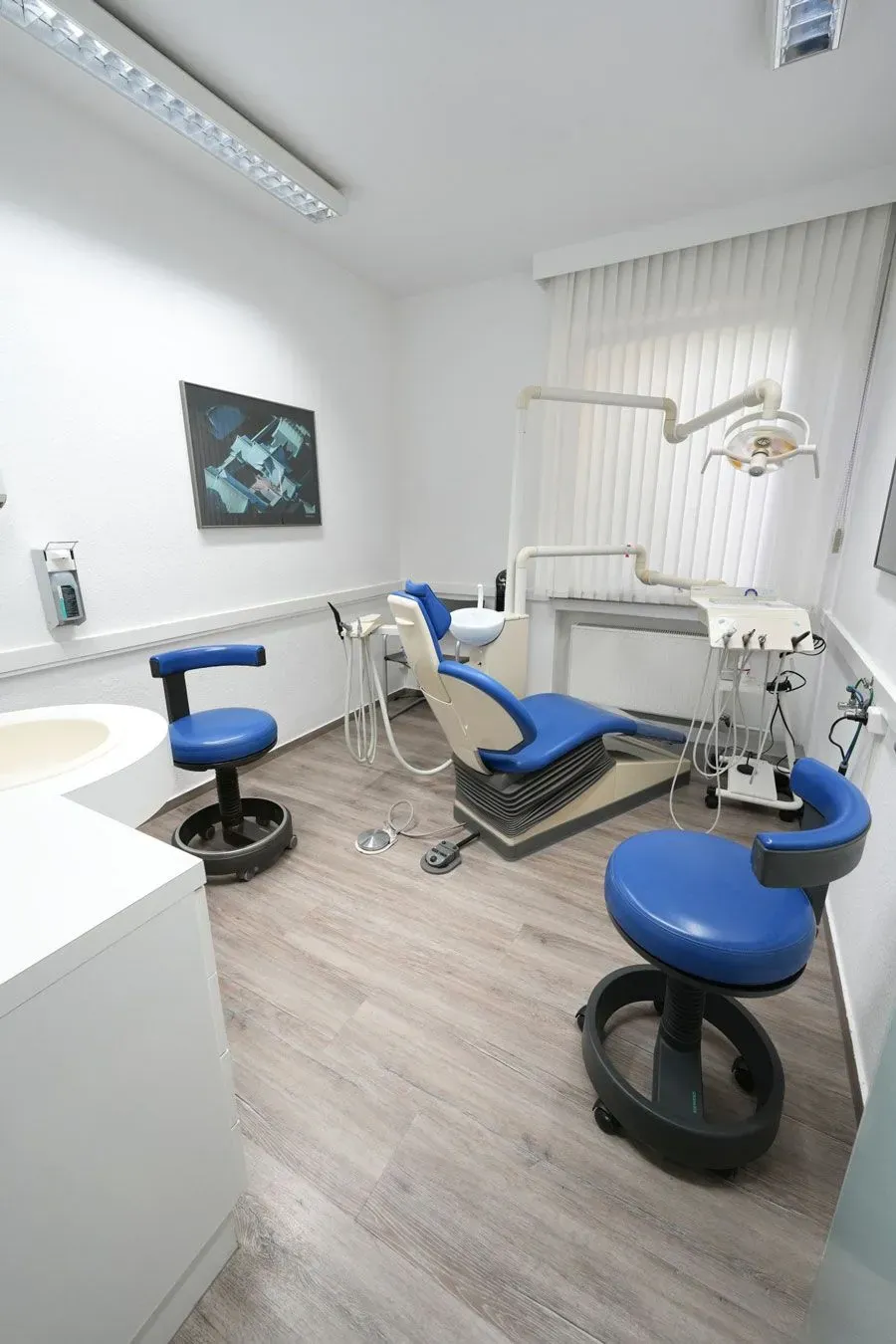 Eine Zahnarztpraxis mit einem blauen Stuhl und einem Waschbecken.