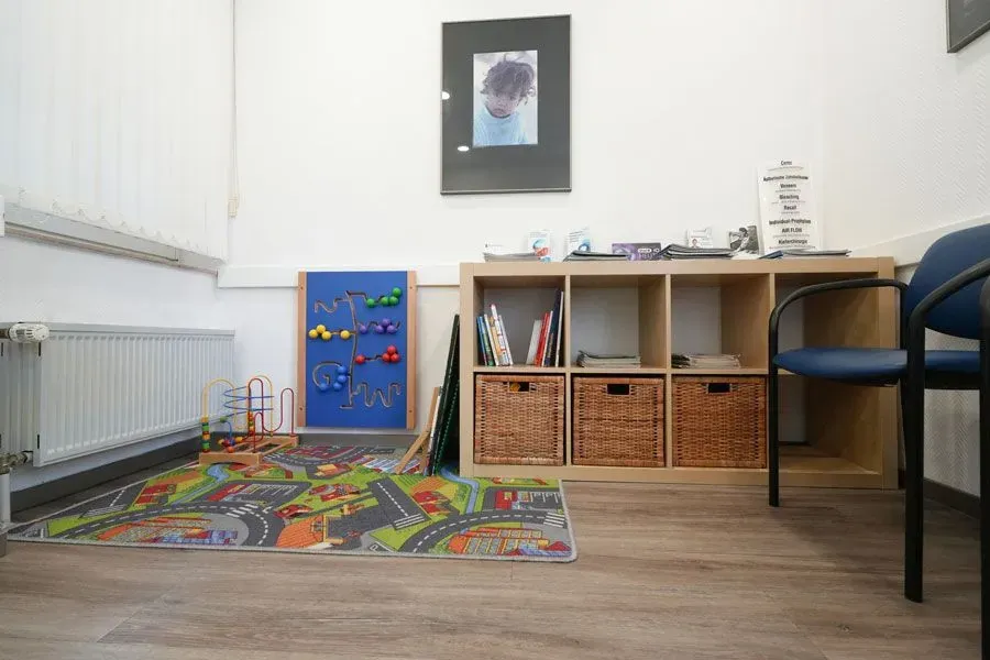 Ein Wartezimmer mit einem Teppich und Spielzeug auf dem Boden.