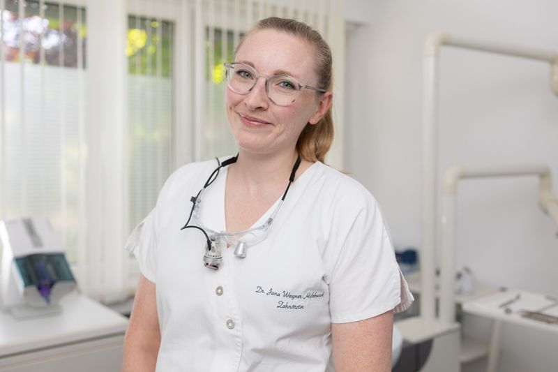Eine Frau mit Brille und weißem Kasack lächelt in die Kamera.