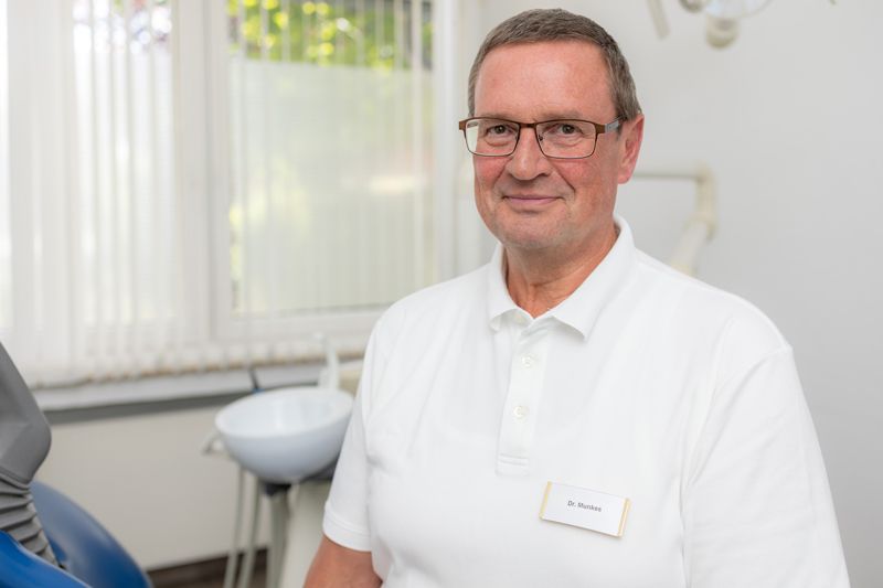 Ein Mann mit Brille und weißem Hemd schaut in die Kamera.