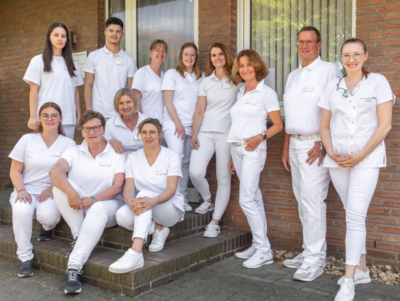 Eine Gruppe von Menschen posiert vor einem Backsteingebäude für ein Foto.